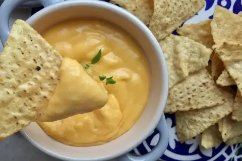 Chrupiące nachos zanurzane w kremowym sosie serowym. Idealna przekąska na imprezę.