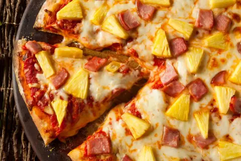 Pyszna pizza z ananasem i szynką, z ciągnącym się serem i chrupiącym ciastem. Idealna na szybki obiad.