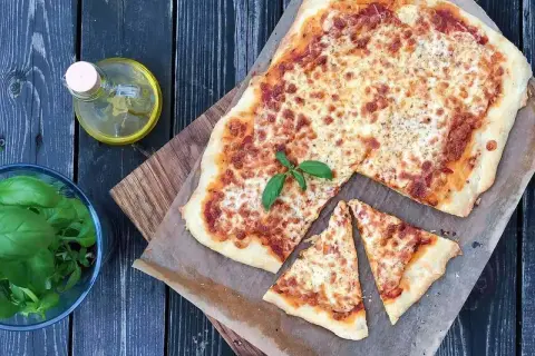 Pyszna pizza waga, z chrupiącym ciastem i ciągnącym serem, obok świeża bazylia i oliwa.