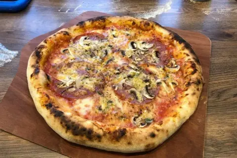 Pyszna pizza z pieczarkami i salami, idealnie wypieczona. Dowodzi, ile nagrzewa się kamień do pizzy, by uzyskać taki efekt.