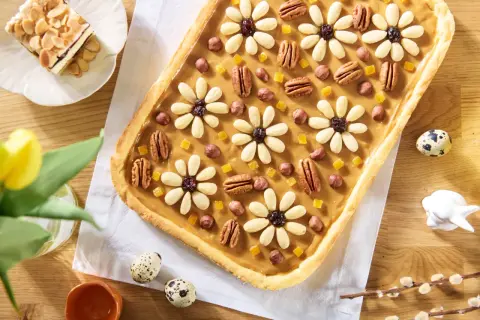 Wielkanocny mazurek ciasto ozdobiony kwiatami z migdałów, orzechami i kandyzowanymi owocami.
