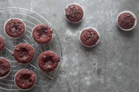 Pyszne babeczki brownie, udekorowane kawałkami czekolady, stygną na kratce.