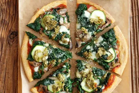 Pyszna pizza ze szpinakiem, cukinią i pieczarkami, polana zielonym pesto. Idealna na lekki obiad.