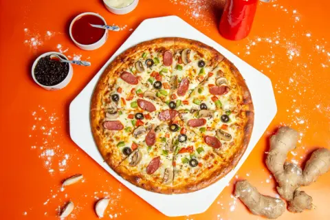 Apetyczna pizza z kiełbasą, pieczarkami i oliwkami. Obok sosy i imbir, idealne dodatki do pizzy.