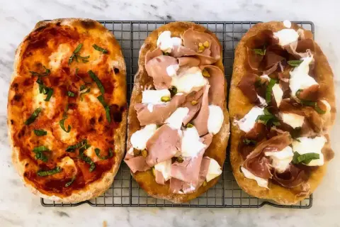 Trzy pyszne pinsy: jedna z sosem pomidorowym i bazylią, druga z mortadelą i pistacjami, trzecia z szynką parmeńską i mozzarellą. Tak wygląda pinsa co to!