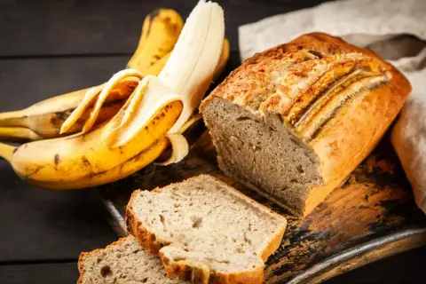 Pyszny chlebek bananowy, idealny pomysł, co zrobić z bananów. Obok leżą świeże banany.
