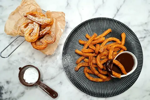 Churros przepis: złociste, chrupiące paluszki posypane cukrem pudrem i cynamonem, podane z gorącą czekoladą. Idealne na deser!