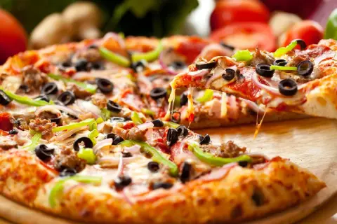 Pyszna pizza na gotowym spodzie z mnóstwem dodatków: salami, oliwkami, papryką i cebulą. Ser ciągnie się apetycznie, gdy podnosimy kawałek.