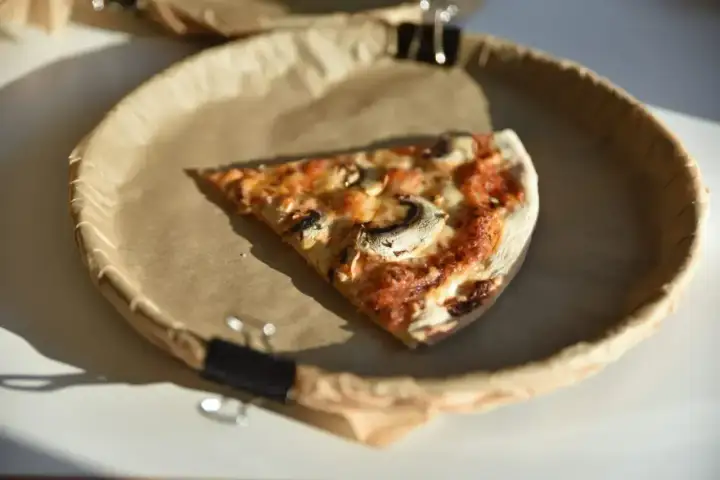 Jeden kawałek pysznej pizzy z pieczarkami na brązowym papierze. Zastanawiasz się, ile kawałków ma pizza?